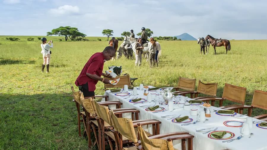 A morning horse riding group arrives at a bush breakfast set up in Chyulu Hills, Kenya